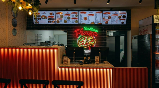 Neon bord Italian Pizza met pizza-logo boven de toonbank van een pizzeria